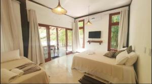 a bedroom with two beds and a tv and windows at Vivant Eco Resort apartamento in Barra Grande