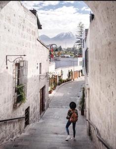 a young child walking down a street between two buildings at la casa de los amigos in Arequipa