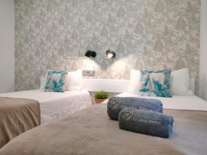 um quarto com 2 camas com almofadas azuis e papel de parede em CANARIAN HOLIDAY HOME - Yumbo Luxury Apartment em Maspalomas
