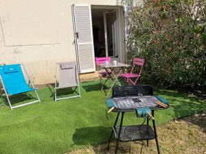 eine Gruppe Stühle und ein Grill in einem Hof in der Unterkunft Appartement Cosy avec jardin privatif et garage in Fontainebleau