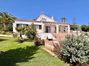 a white house with palm trees in a yard at Villa Ona in Son Bou