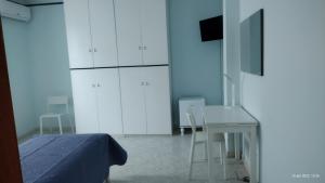 een slaapkamer met een bed, een bureau en witte kasten bij Villa Grazia in Ladispoli
