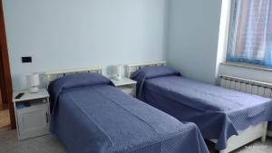 twee bedden in een kamer met blauwe dekbedden bij Villa Grazia in Ladispoli