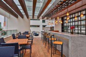 un restaurante con mesas y sillas de madera y ventanas en América apart-hotel, en Campos dos Goytacazes