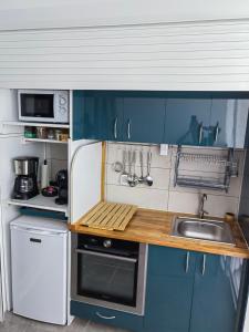 uma pequena cozinha com armários azuis e um lavatório em Blue Dream em Le Diamant
