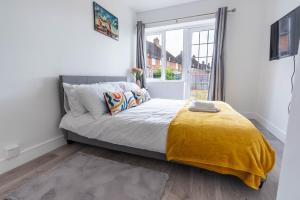 a bed with a yellow blanket in a room with a window at Flat 04 Studio flat close to Aylesbury town and Station Free Parking in Buckinghamshire