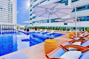 una piscina con sillas y sombrillas junto a un edificio en América apart-hotel, en Campos dos Goytacazes