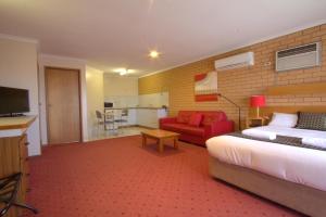 a hotel room with a bed and a red couch at Blue Whale Motor Inn & Apartments in Warrnambool
