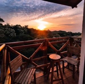 puesta de sol en un balcón con 2 bancos y un taburete en Hotel Quinto Sol, en Mazunte