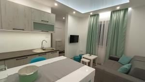 a kitchen and a living room with a couch and a table at Apartman Mauna De Luxe in Bogatić
