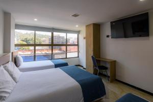 a hotel room with two beds and a large window at Hotel Med Estadio in Medellín