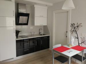 a kitchen with black cabinets and a table and a white refrigerator at Bonito Loft en Ermua. Cómodo y funcional. in Ermua