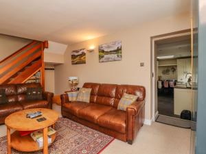 a living room with a leather couch and a table at Fountains Cottage in Malham