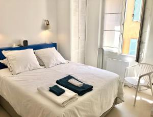 1 cama blanca con toallas y 1 silla en una habitación en San Estello, en Sanary-sur-Mer