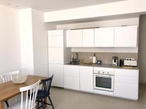 a kitchen with white cabinets and a wooden table at San Estello in Sanary-sur-Mer