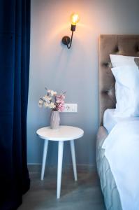 a table with a vase of flowers on it next to a bed at Boutique Residence Arion in Rovinj