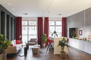a living room with red curtains and a kitchen at NH Collection Hamburg City in Hamburg