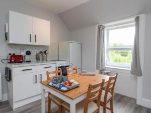 a kitchen with a wooden table and chairs and a kitchen with white cabinets at The Knowe Upper in Taynuilt
