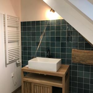 a bathroom with a sink and a green tiled wall at Escale de Gerbold in Gratot