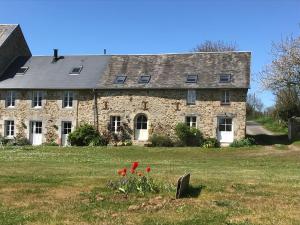 an old stone house with red flowers in front of it at Escale de Gerbold in Gratot