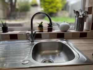 a kitchen sink with a faucet next to a window at Ty Collective - Near Town Centre in Dowlais +24 photos