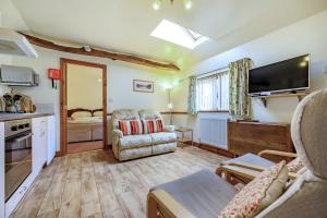 a living room with a couch and a tv and a kitchen at Pea Top Cottage in Culgaith