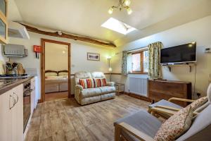 un soggiorno con divano, sedia e TV di Pea Top Cottage a Culgaith