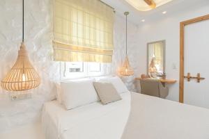 a white bedroom with a white bed and two lamps at Blue Sky Summer in Naxos Chora
