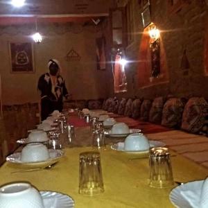 una mesa con platos blancos y una persona en una habitación en Riad gnaoua khamlia en Merzouga