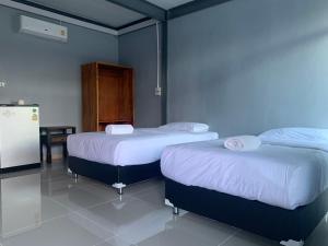 um quarto com 2 camas e um frigorífico em บ้านพิชชา ที่พักใจกลางเมืองปราณบุรี em Ban Khao Noi