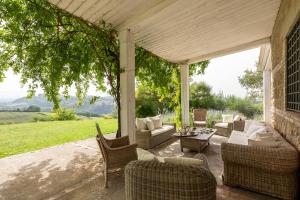 un porche con sofás, sillas y una mesa en Tenuta Colle Sala - Country House & Suites, en Magliano Sabina
