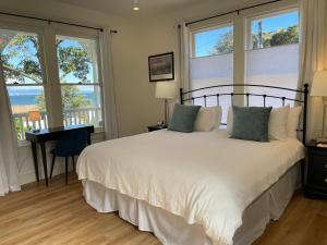 a bedroom with a bed and a desk and windows at The Gables Inn Sausalito in Sausalito