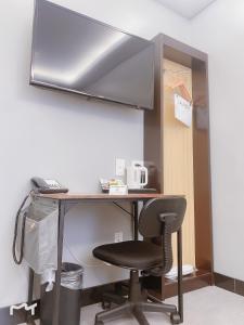 a desk with a chair and a monitor on a wall at Madison LES Hotel in New York