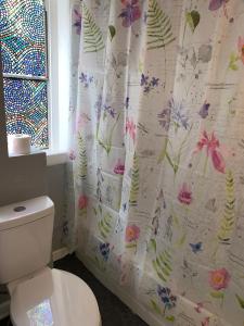 a bathroom with a toilet with a flower shower curtain at Historical District 2BDRM built in 1910 in Lynchburg