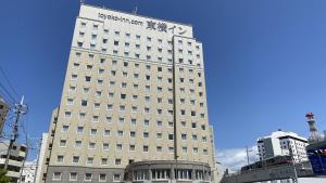 Toyoko Inn Okinawa Naha Asahibashi Ekimae في ناها: مبنى أبيض طويل عليه علامة