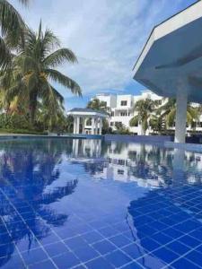 una piscina con suelo de baldosa azul y palmeras en Wave nSea Monterrico, en Monterrico