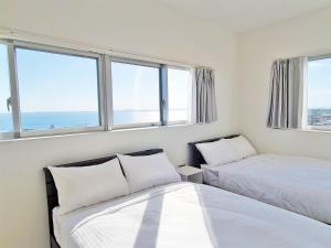 two beds in a room with two windows at HOTEL Kuu in Miyako Island