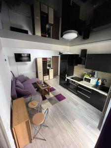 ein Wohnzimmer mit einem lila Sofa und einer Küche in der Unterkunft Roxy apartament in Constanţa
