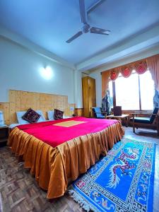 a bedroom with a large bed with a red blanket at Hotel Snow Mountain Mall Road in Manāli