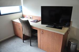a desk with a computer and a television at City Park Hotel in Melbourne