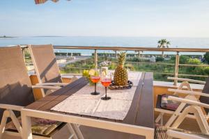 a table with wine glasses on a balcony with the ocean at Apartment Traversa in Novalja
