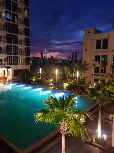 una gran piscina con palmeras y edificios por la noche en Capitol Park Minimum Stay 2 Nights, en Yakarta