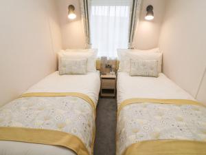 two twin beds in a small room with a window at Langdale Lodge in Carnforth