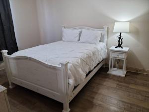 a bedroom with a white bed and a nightstand with a lamp at Chateau 15 in Hammond