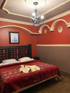 een slaapkamer met een bed met rode muren en een kroonluchter bij Hotel Plaza in San Martín Texmelucan de Labastida
