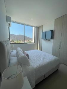 1 dormitorio con cama y ventana grande en Apartamento en Santa Marta - Samaria club de playa, en Santa Marta