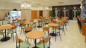 熊本Toyoko Inn Kumamoto Ekimae的自助餐厅里有桌椅的餐厅