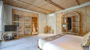 a bedroom with a large bed and a tv at Pravasa Gili Resort by KajaNe in Gili Meno