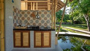 a kitchen with a sink on a wall next to a pond at Pravasa Gili Resort by KajaNe in Gili Meno
