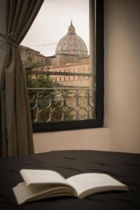 an open book on a bed in front of a window at My Rooms in Rome